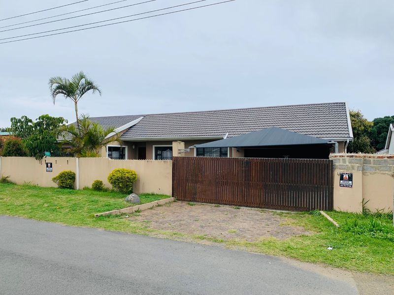 Front elevation of a single-story house featuring a tiled roof, perimeter walling, a timber gate, and a shade sail carport.