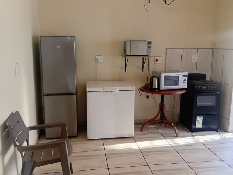 A basic kitchen area featuring tiled flooring and a freestanding stove, currently lacking built-in cabinetry and proper counter space.