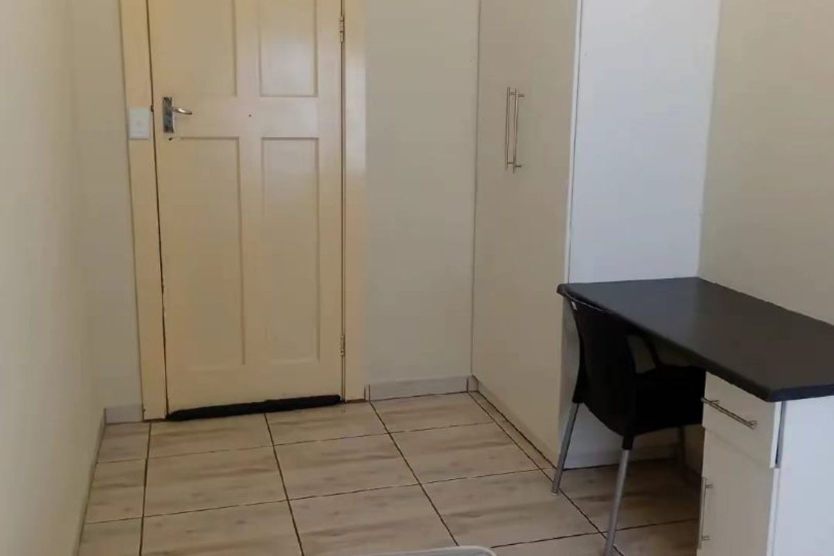 A functional bedroom featuring tiled flooring and a built-in wardrobe, providing practical storage space.