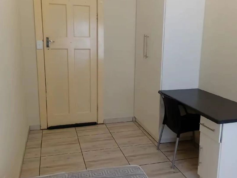 A functional bedroom featuring tiled flooring and a built-in wardrobe, providing practical storage space.