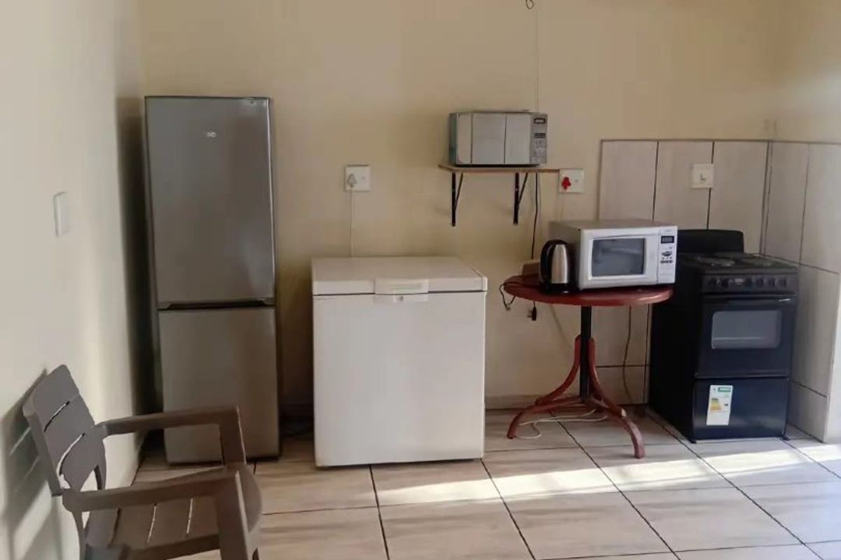 A basic kitchen area featuring tiled flooring, a tiled splashback, and a freestanding oven, currently requiring cosmetic updates and electrical maintenance.