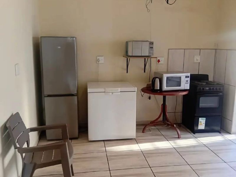 A basic kitchen area featuring tiled flooring, a tiled splashback, and a freestanding oven, currently requiring cosmetic updates and electrical maintenance.