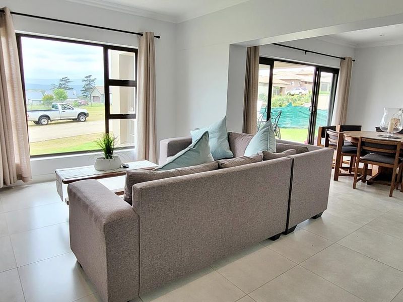 Spacious open-plan living and dining area featuring large windows, sliding glass doors, and neutral tiled flooring, offering a bright and airy atmosphere.