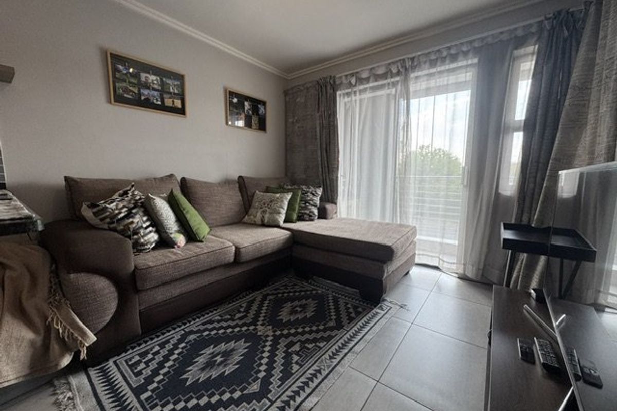A comfortable living room featuring tiled flooring and a large sliding glass door that provides access to an outdoor area.