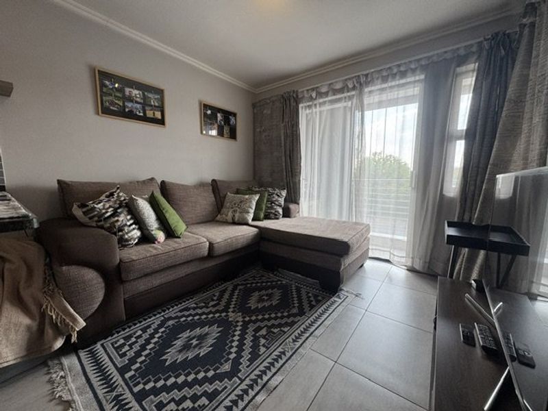 A comfortable living room featuring tiled flooring and a large sliding glass door that provides access to an outdoor area.