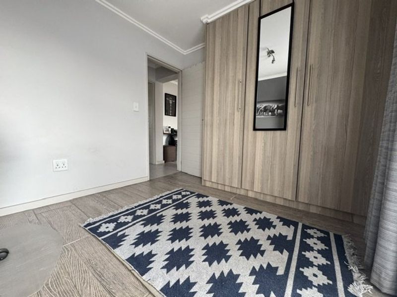 A bedroom featuring light wood-finish built-in cupboards, tiled flooring, and coved ceiling details.