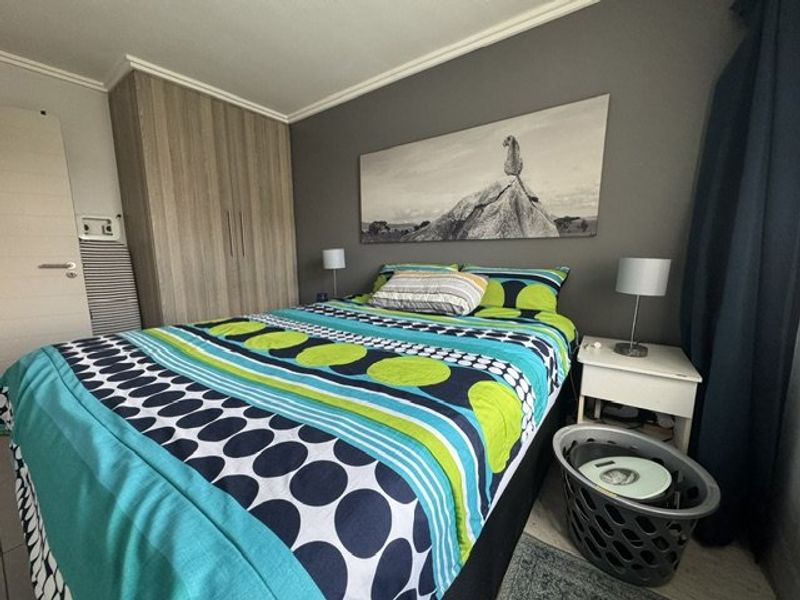 A well-maintained bedroom featuring a built-in wardrobe, neutral grey accent wall, and classic coving detail, offering a functional and comfortable living space.