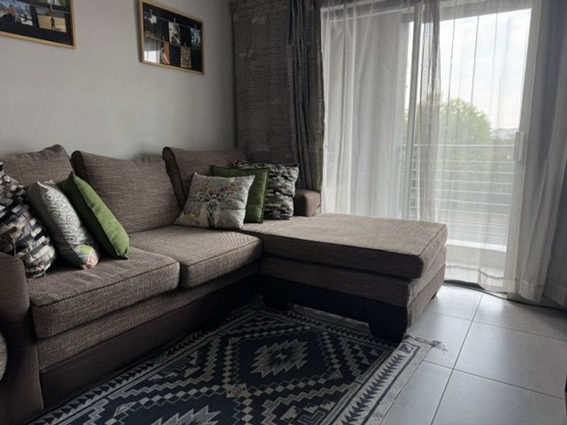 A living room area featuring tiled flooring and a large sliding glass door providing access to an outdoor balcony space.