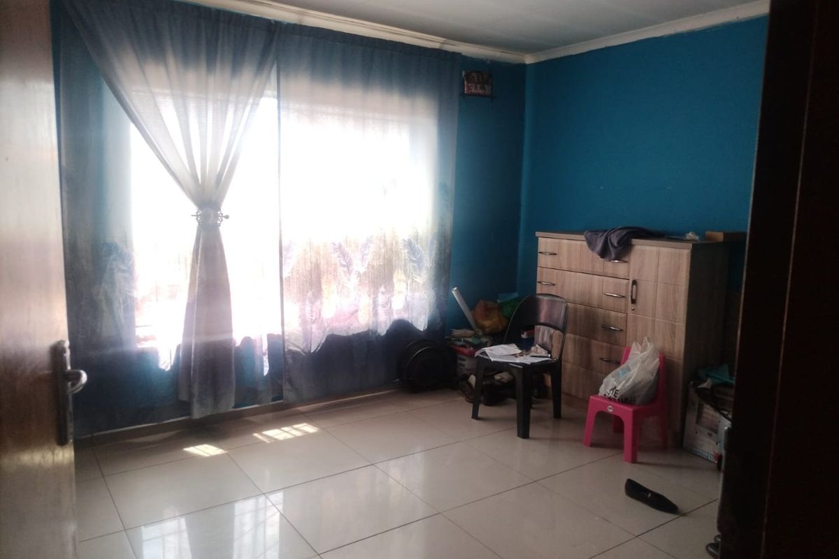 A bedroom featuring tiled flooring and a large sliding glass door that provides natural light.