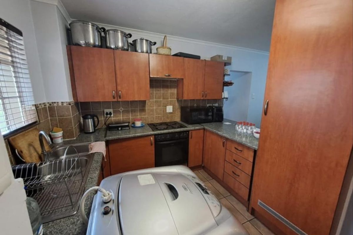 Functional kitchen featuring wooden cabinetry, granite countertops, tiled backsplash, and built-in oven and hob, providing a practical workspace for daily cooking.