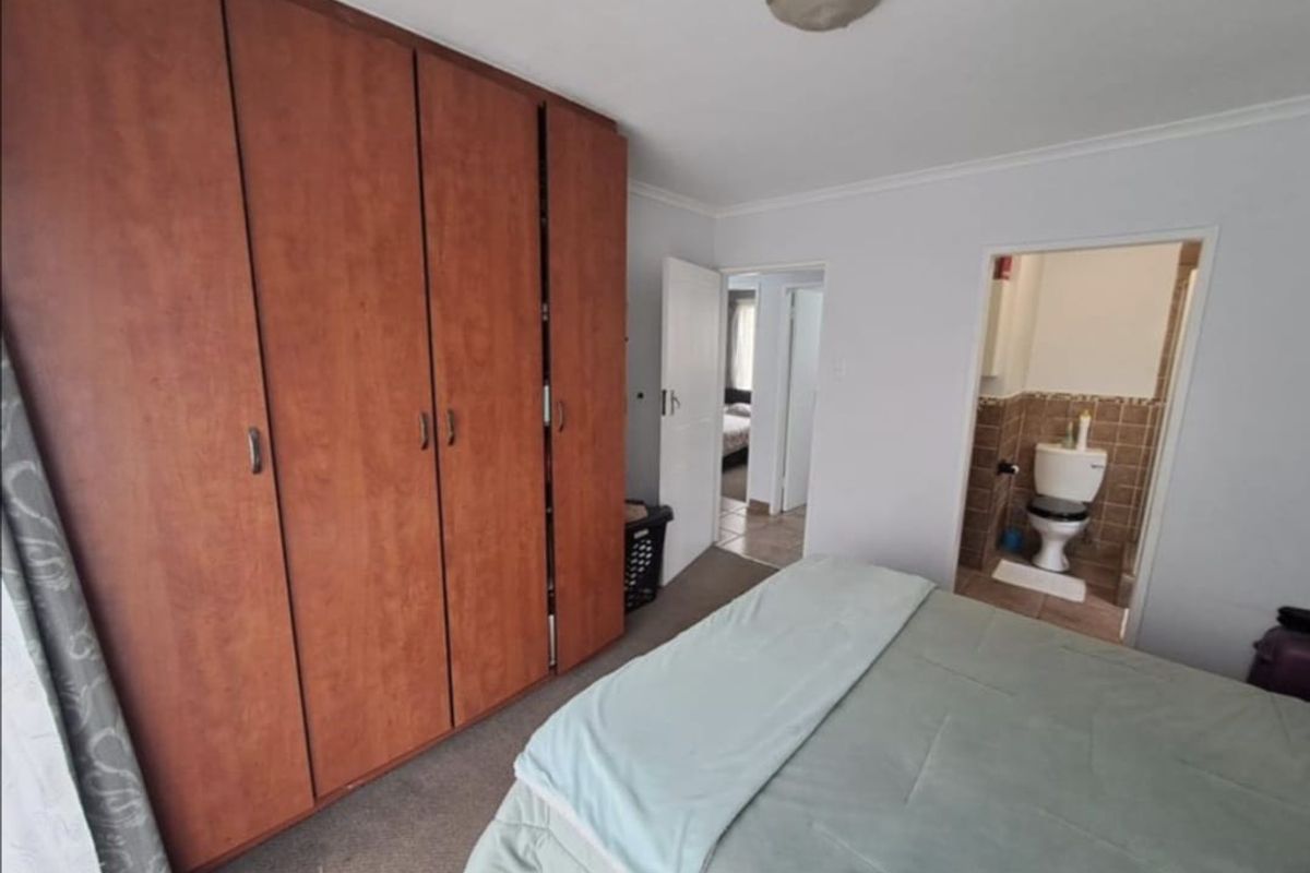 Bedroom featuring a large built-in wooden wardrobe and an attached en-suite bathroom with a toilet.
