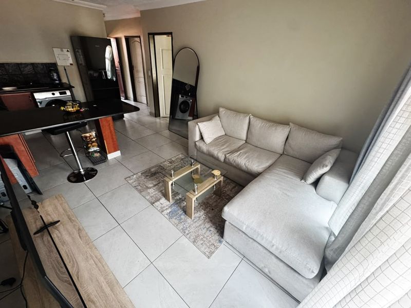 Open-plan living area featuring tiled flooring and a functional kitchen with a central island, creating a cohesive and versatile space.