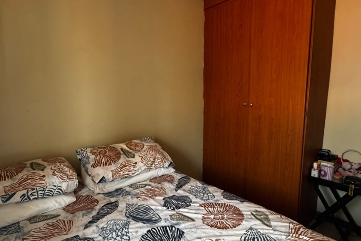 A bedroom featuring a built-in wooden wardrobe and a textured ceiling finish.