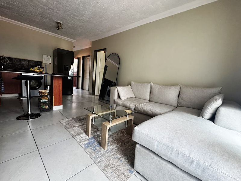 Open plan living area featuring tiled flooring, a breakfast bar, and coved ceilings, providing a functional space for dining and relaxation.