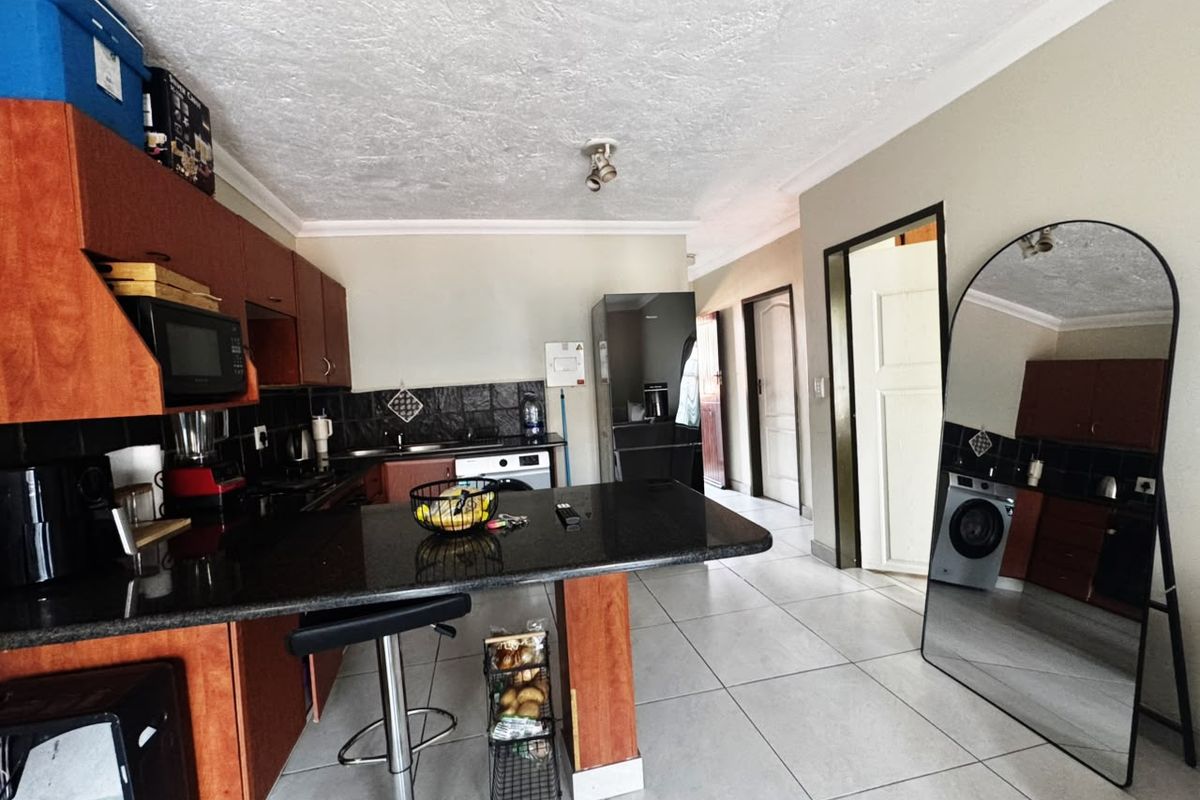 A functional kitchen featuring dark wood cabinetry, granite countertops, and tiled flooring, offering a practical layout with integrated appliance space.
