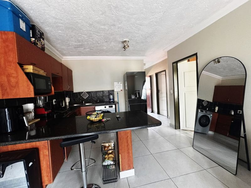 A functional kitchen featuring dark wood cabinetry, granite countertops, and tiled flooring, offering a practical layout with integrated appliance space.