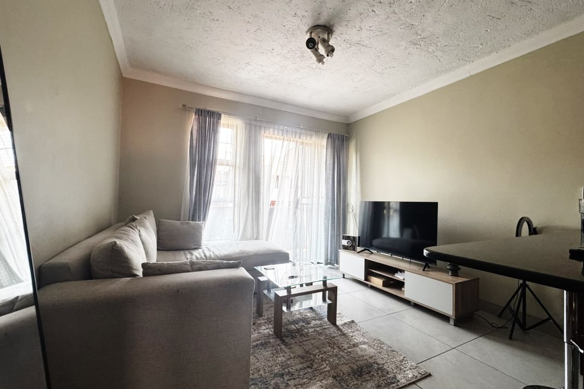 A comfortable living room featuring tiled flooring, a coved ceiling, and a sliding glass door that provides natural light.