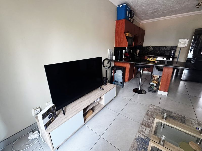 Open-plan living area featuring tiled floors and a functional kitchen with granite countertops and built-in cabinetry.