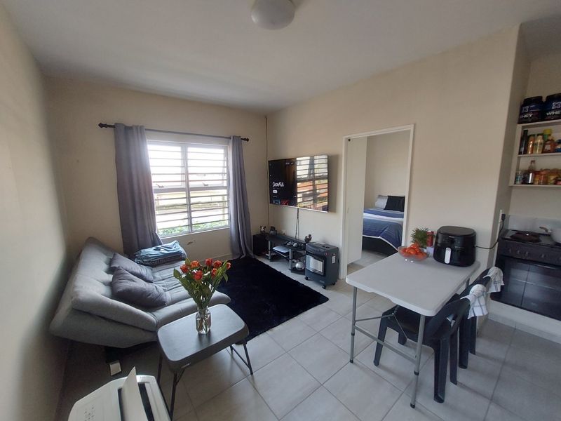 Open-plan living and kitchen area featuring tiled flooring, built-in cabinetry, and a functional layout with direct access to an adjacent bedroom.