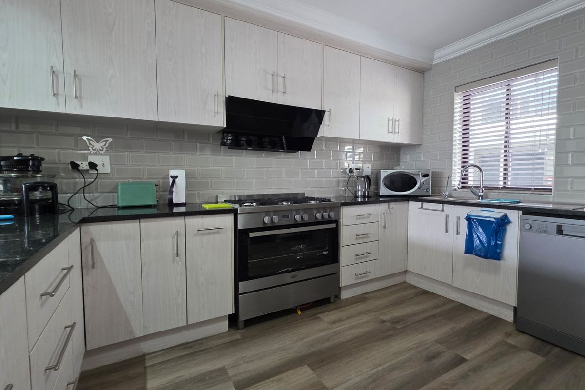 Modern kitchen featuring light wood-grain cabinetry, granite countertops, subway tile backsplash, and integrated stainless steel appliances including a gas hob and oven.