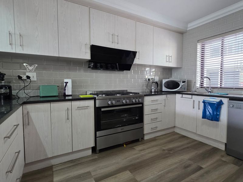 Modern kitchen featuring light wood-grain cabinetry, granite countertops, subway tile backsplash, and integrated stainless steel appliances including a gas hob and oven.