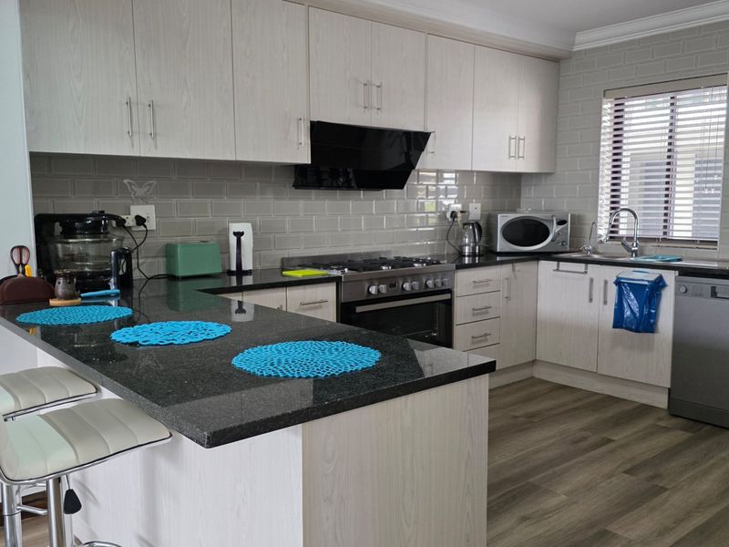 Modern kitchen featuring light wood cabinetry, granite countertops, subway tile backsplash, and integrated appliances including a gas hob and oven.