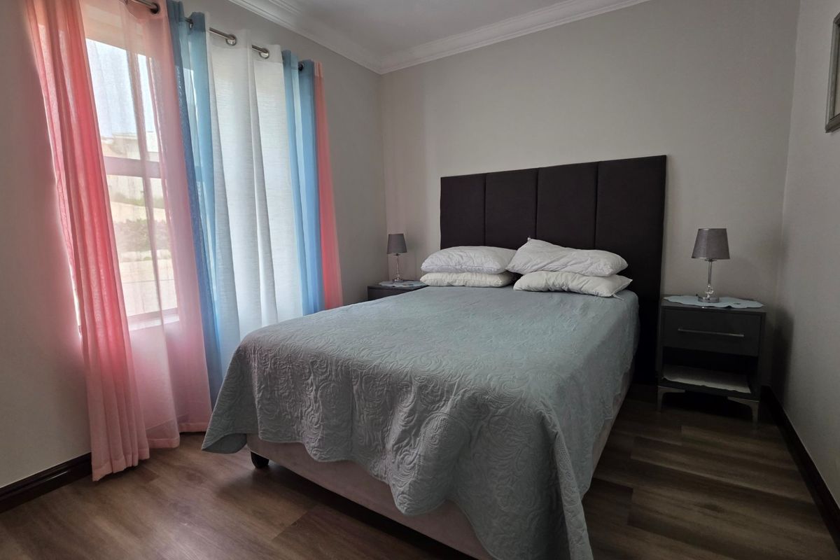 A well-maintained bedroom featuring laminate flooring and neutral wall finishes, providing a comfortable and functional living space.