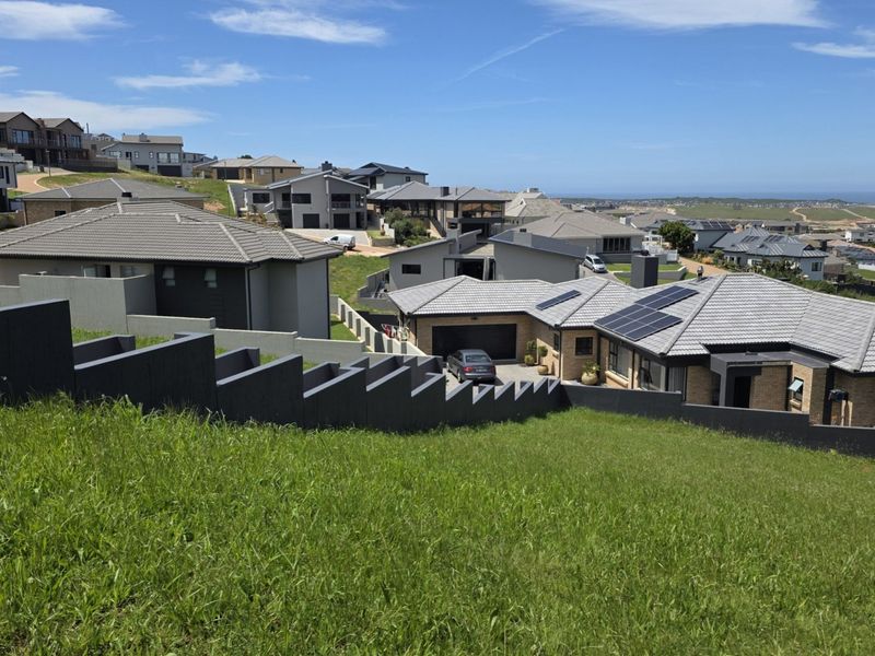 Elevated view overlooking a residential estate with sloped terrain and a prominent retaining wall in the foreground.