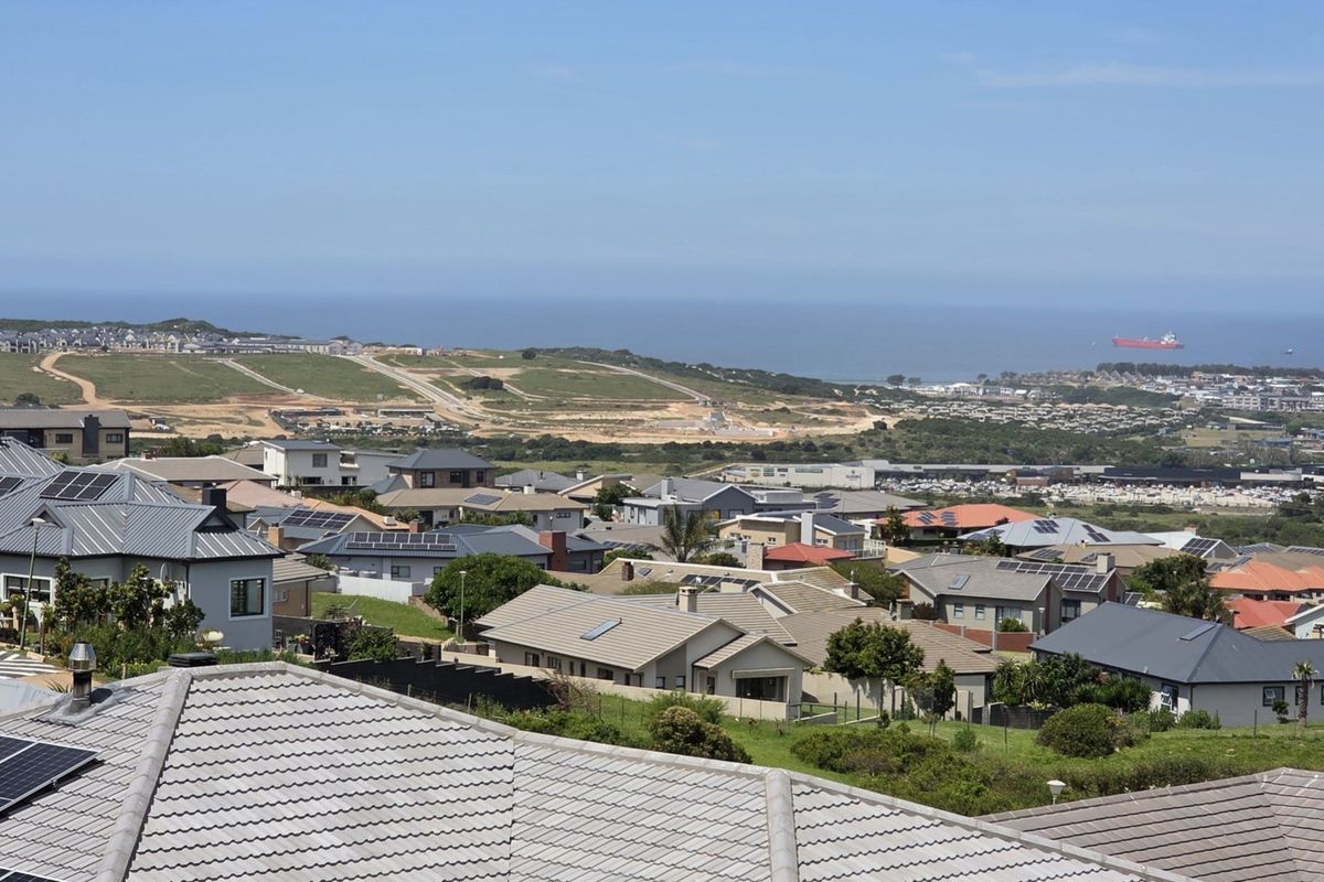 An elevated panoramic view overlooking a residential neighborhood with a distant coastal landscape and ocean horizon.