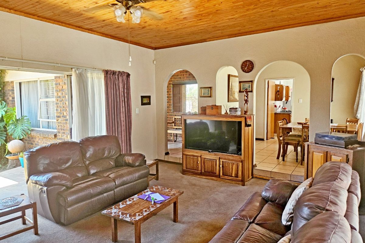 Spacious living room featuring a warm timber ceiling, ceiling fan, and classic arched doorways leading to the dining area and kitchen.