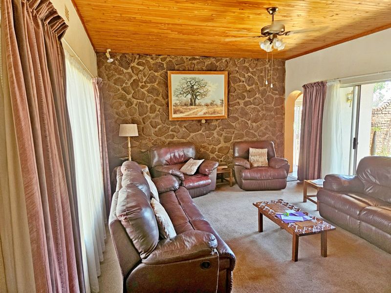 Spacious living room featuring a rustic stone feature wall, warm timber tongue and groove ceiling, and direct access to the outdoor area via sliding doors.