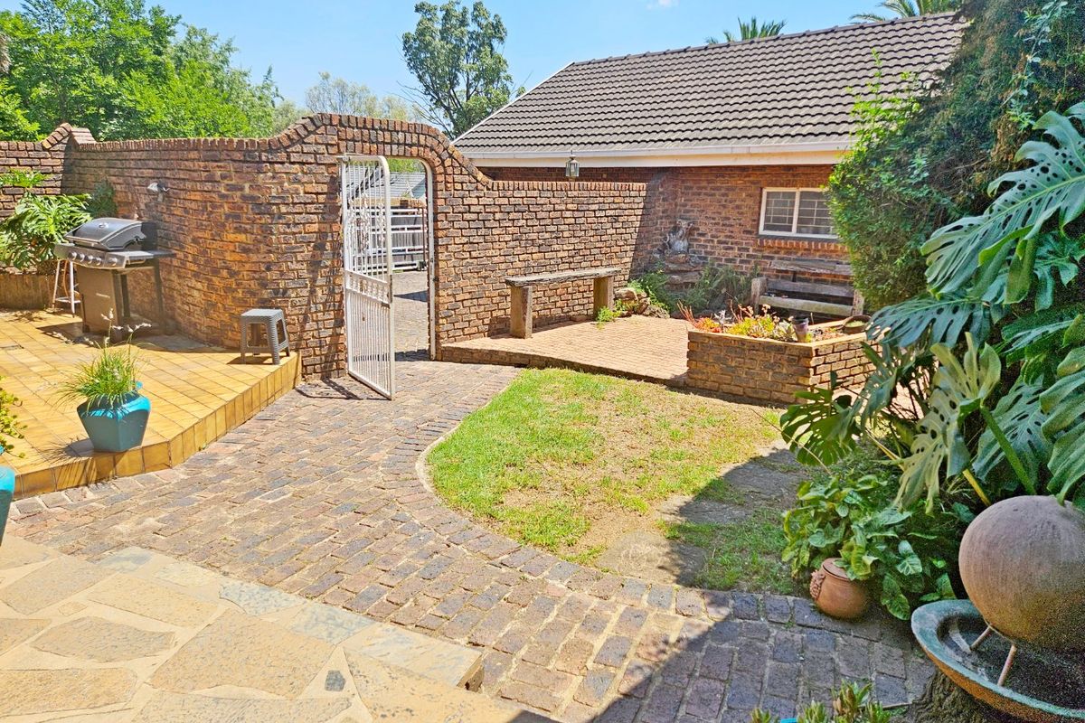 A private rear courtyard featuring brick paving, a tiled patio area, and a brick boundary wall with a gated entrance.