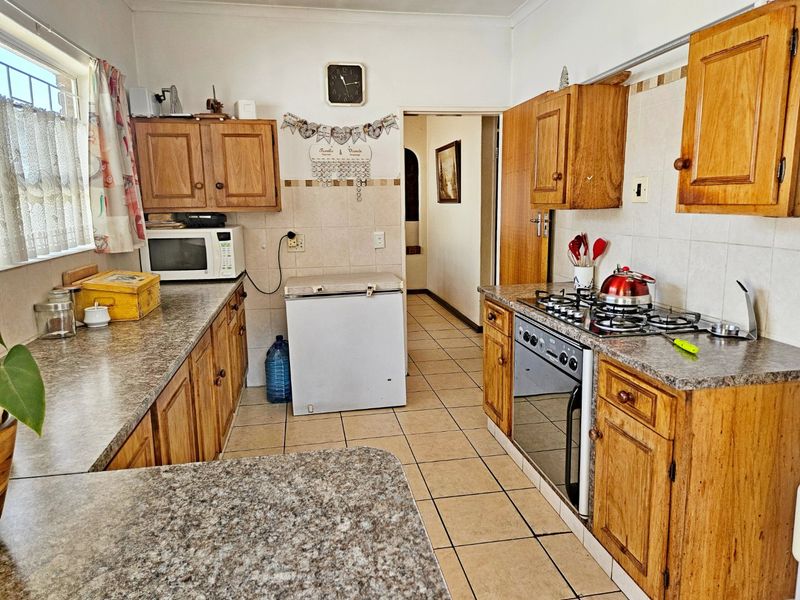 A functional kitchen featuring traditional wooden cabinetry, laminate countertops, a gas hob, and an integrated oven with tiled flooring and backsplash.