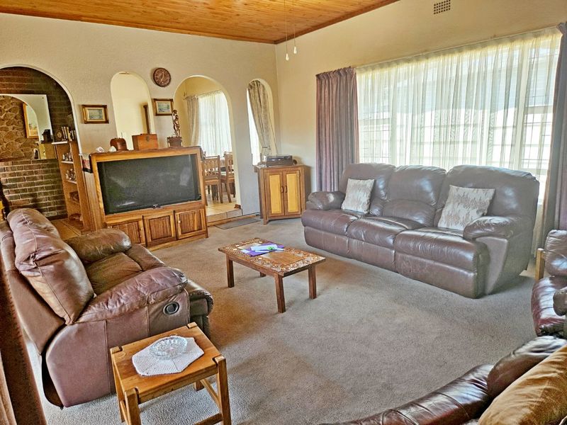 Spacious living room featuring a timber ceiling, brick fireplace detail, and arched doorways leading to adjacent living areas.