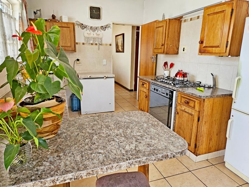 A functional kitchen featuring wooden cabinetry, granite-look countertops, a gas hob, and a built-in oven with tiled flooring and backsplash.