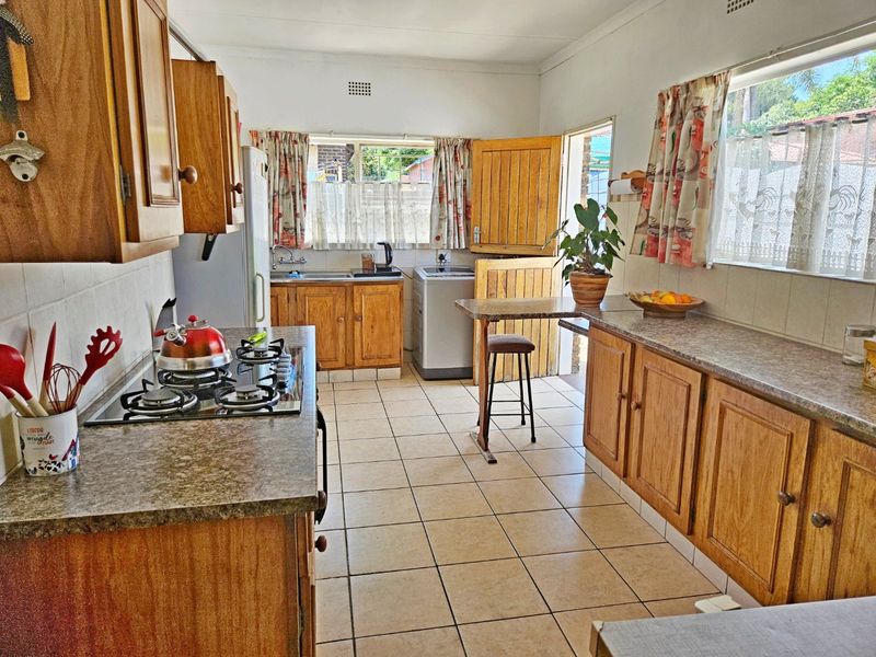A functional kitchen featuring wooden cabinetry, laminate countertops, a gas hob, and tiled flooring with direct access to the exterior via a stable door.