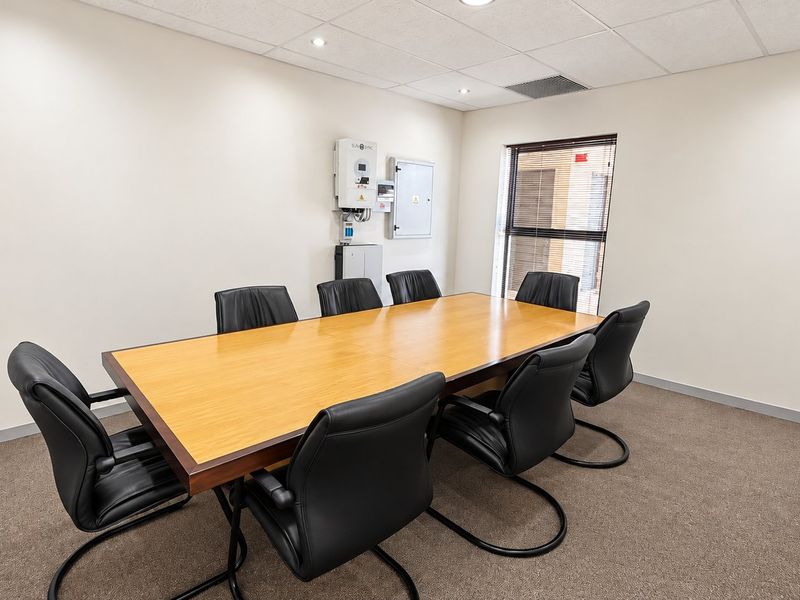 A professional office meeting room featuring a large conference table, carpeted flooring, suspended ceiling with recessed lighting, and integrated solar power infrastructure.