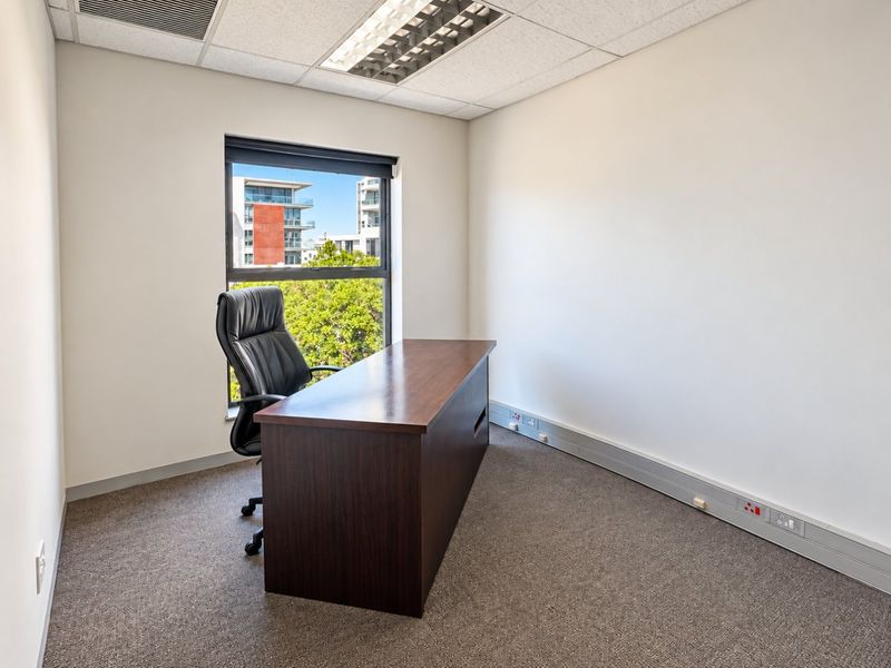 A professional office space featuring carpeted flooring, suspended ceiling with recessed lighting, and integrated wall trunking for power and data connectivity.