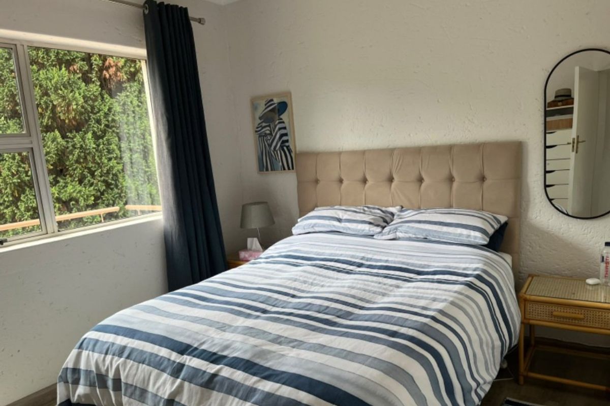 A bedroom featuring a large window with natural light and textured wall finishes, providing a comfortable and functional living space.