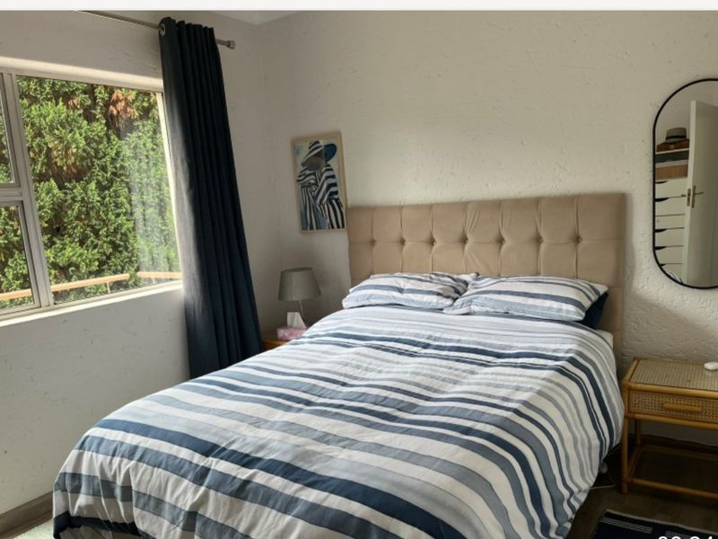 A bedroom featuring a large window with natural light and textured wall finishes, providing a comfortable and functional living space.