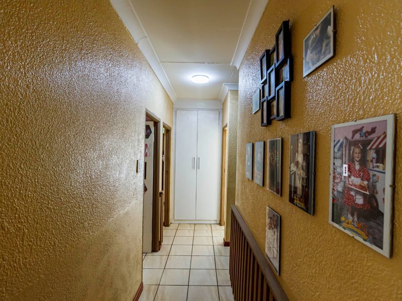 A functional hallway featuring tiled flooring, a built-in storage cupboard, and textured wall finishes.