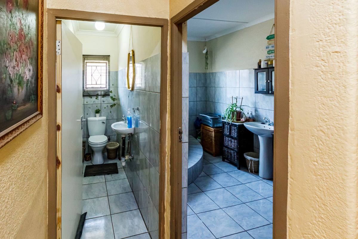 A view through doorways into two adjacent bathrooms featuring tiled walls, ceramic flooring, pedestal sinks, and a toilet.