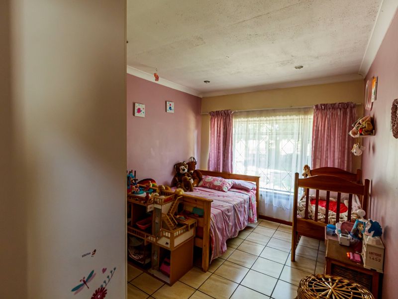 A bedroom featuring tiled flooring, recessed ceiling lighting, and a window fitted with a security gate.