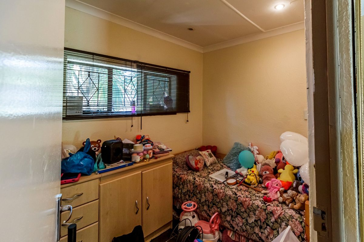 A compact bedroom featuring a window with security bars, venetian blinds, and recessed ceiling lighting.