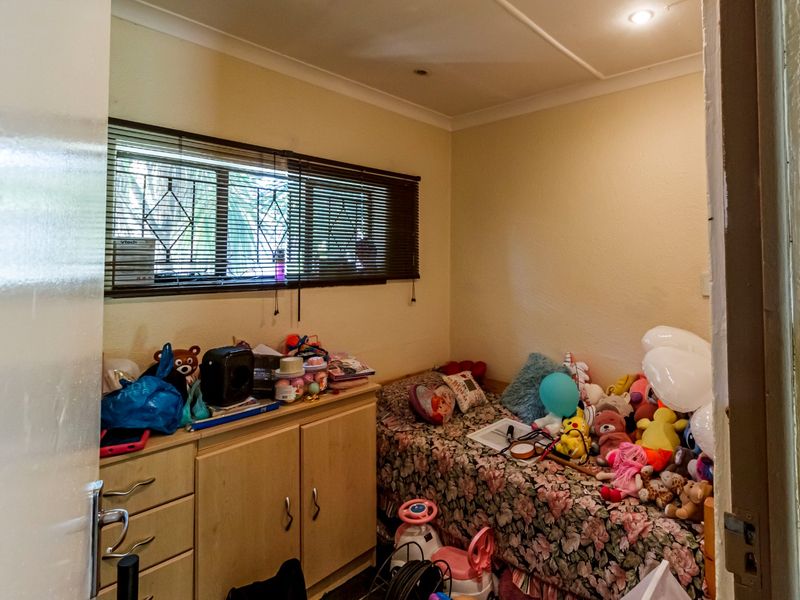 A compact bedroom featuring a window with security bars, venetian blinds, and recessed ceiling lighting.