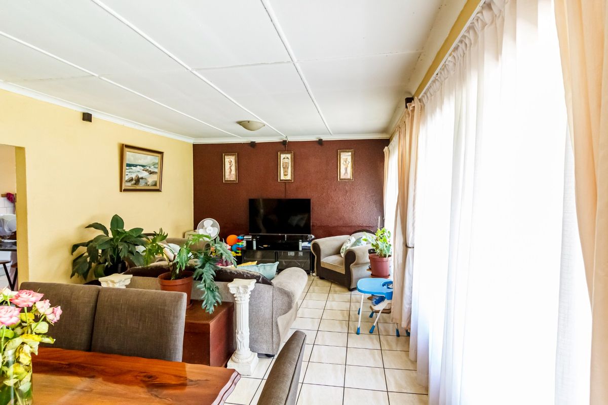 Open plan living and dining area featuring tiled flooring and large windows, providing a functional space with potential for modern updates.