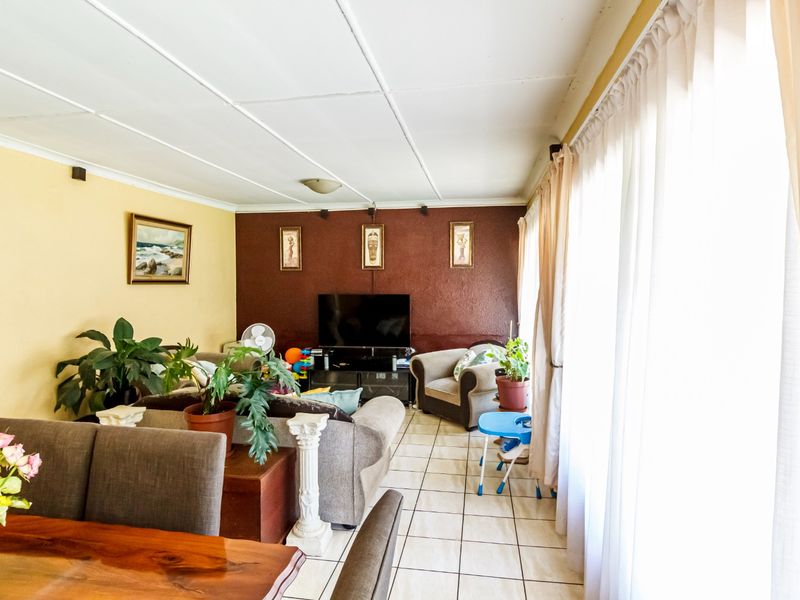Open plan living and dining area featuring tiled flooring and large windows, providing a functional space with potential for modern updates.