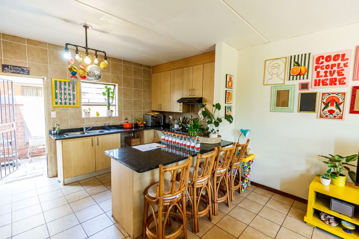 A functional kitchen featuring light wood cabinetry, granite countertops, a breakfast bar, and tiled flooring with direct access to an outdoor area.