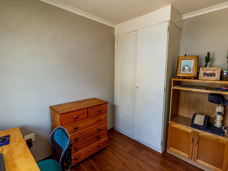 A bedroom featuring laminate flooring and a built-in wardrobe with neutral wall finishes.