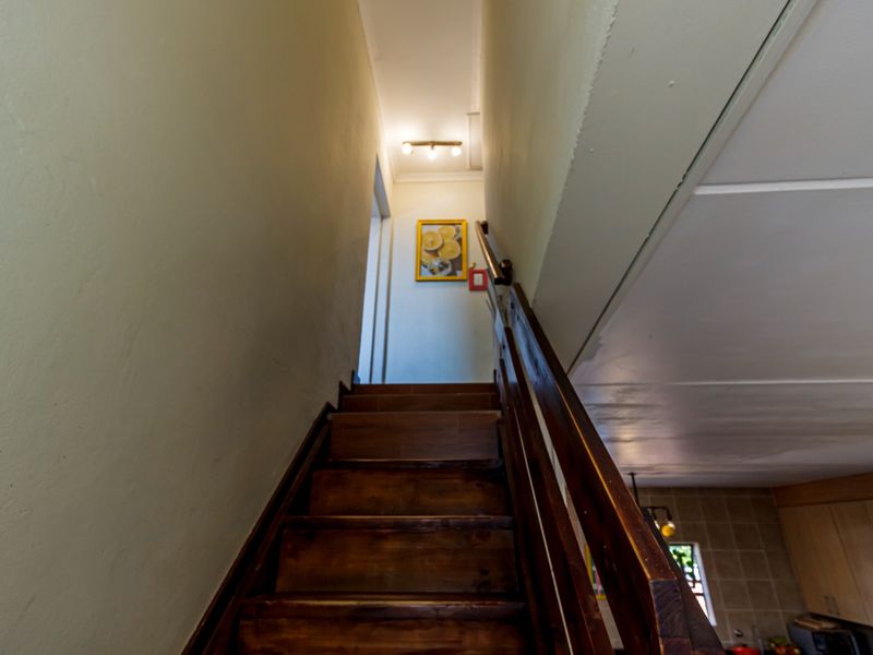 A wooden staircase leading to an upper level, featuring a sturdy wooden handrail and neutral wall finishes.